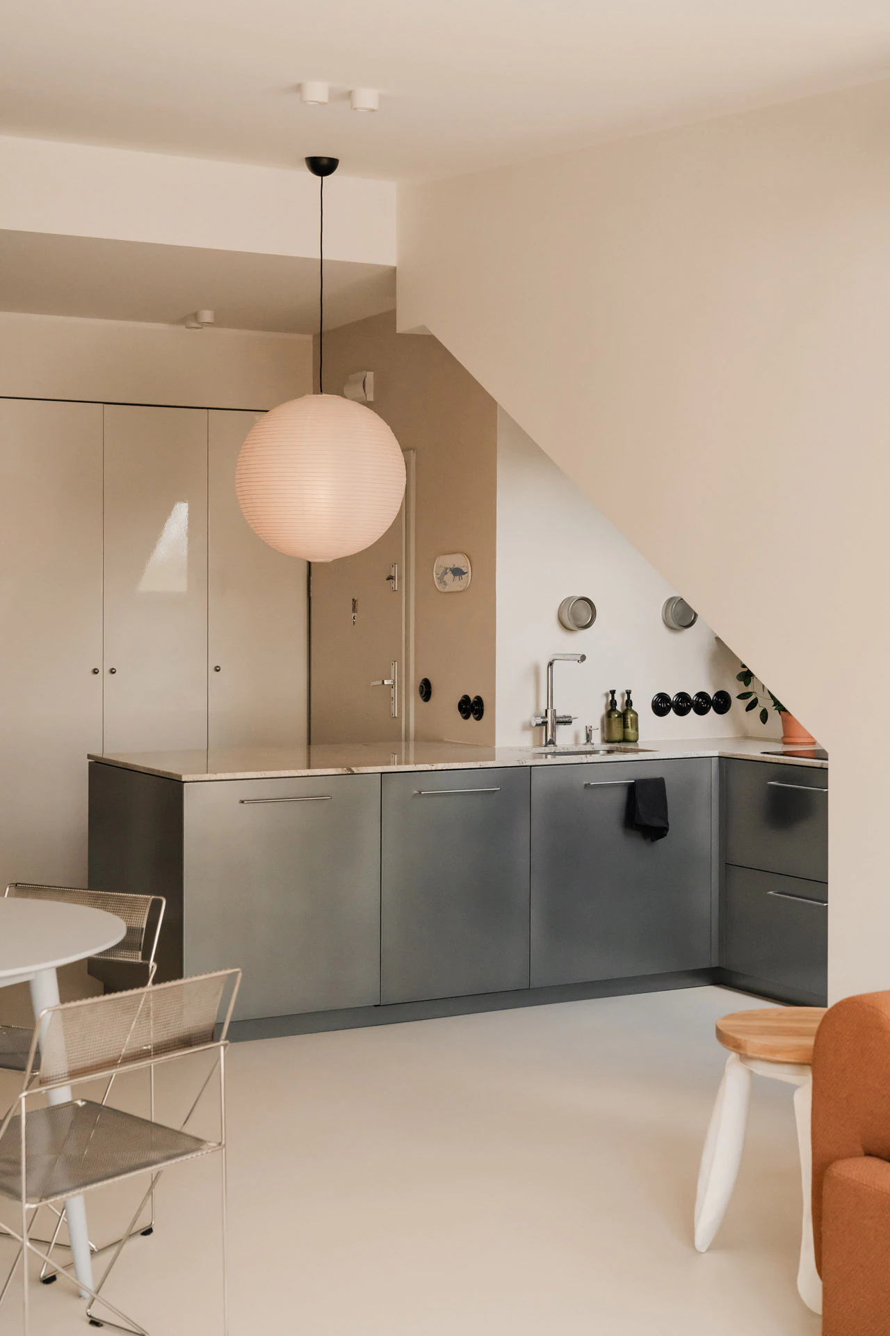 Minimalist attic kitchen with grey cabinets and paper lantern pendant